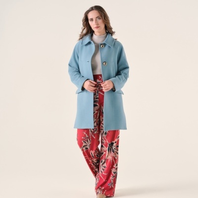 Mulher com casaco azul claro e calças vermelhas com padrão floral