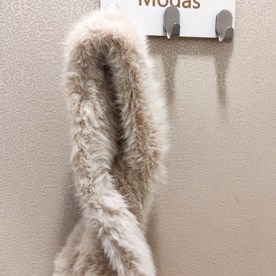 Cachecol de pêlo sintético castanho claro pendurado num cabide branco com ganchos