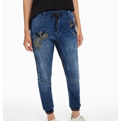 Calças de ganga azuis com bordados dourados e ténis brancos com letras coloridas