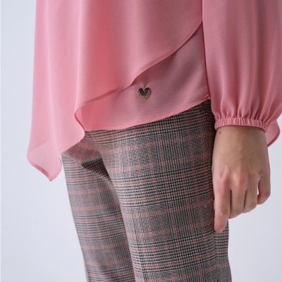 Blusa rosa fluida com aplicação metálica de coração e calça xadrez cinza e rosa.