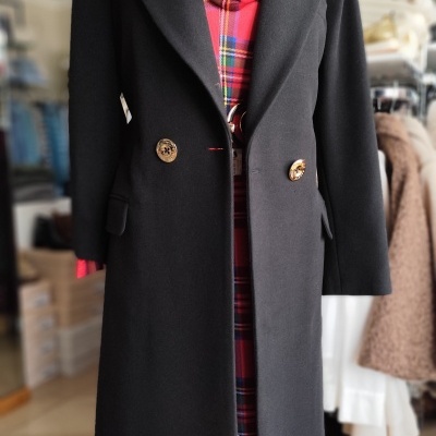 Casaco preto comprido com botões dourados sobre vestido vermelho xadrez em manequim