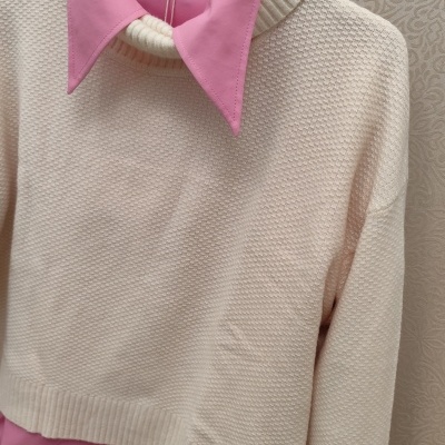 Conjunto camisa rosa com camisola creme pendurado num cabide preto