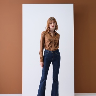 Mulher com camisa castanha e calças de ganga azul escura