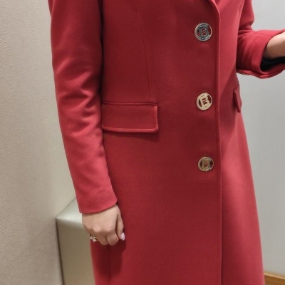 Casaco comprido vermelho com botões e gola lapela, fotografia interior.