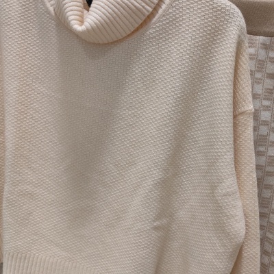 Conjunto de duas peças de malha creme com padrão de textura penduradas em cabides.