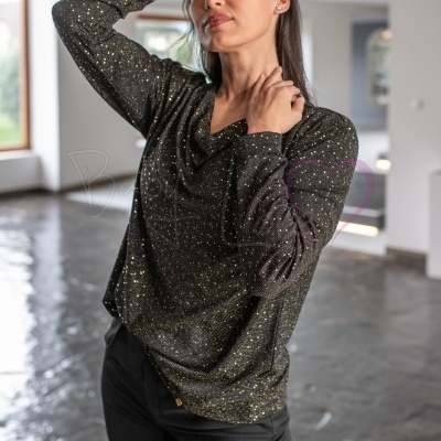 Blusa preta com pontos dourados e gola ampla em ambiente interior