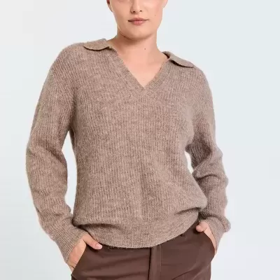 Mulher com camisola castanha clara de malha e calças castanhas escuras