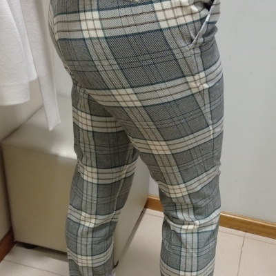 Calças às riscas cinza, bege e azul com botins brancos em ambiente interior