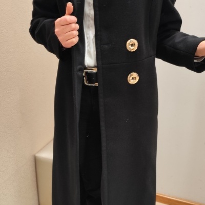 Casaco longo preto com botões dourados usado numa pessoa