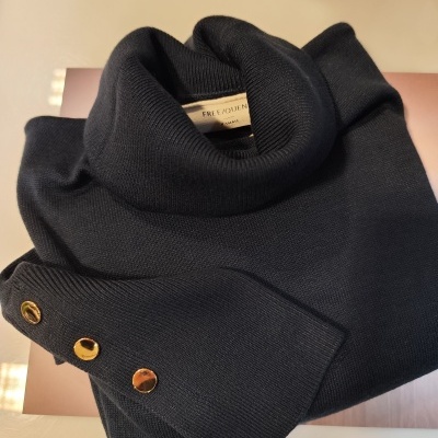 Camisola preta de malha com gola alta e botões dourados no punho.