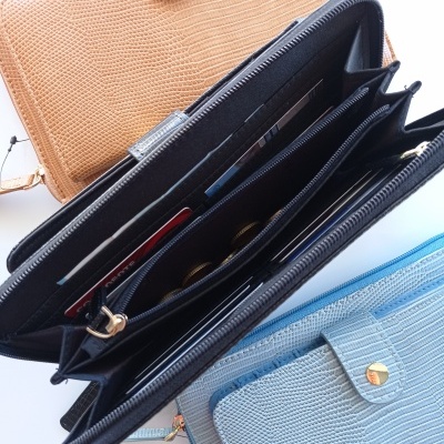 Três carteiras clutch texturizadas em pele imitação crocodilo, castanho, azul claro e preta, interior da preta aberto com moedas e cartões