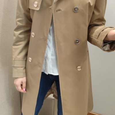 Sobretudo bege com botões dourados em ambiente interior