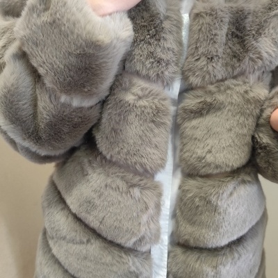 Casaco de pelúcia cinzento macio usado por pessoa com camisa branca e anel prateado