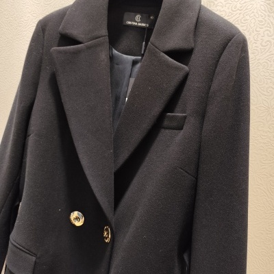 Blazer preto feminino com botões dourados pendurado num cabide