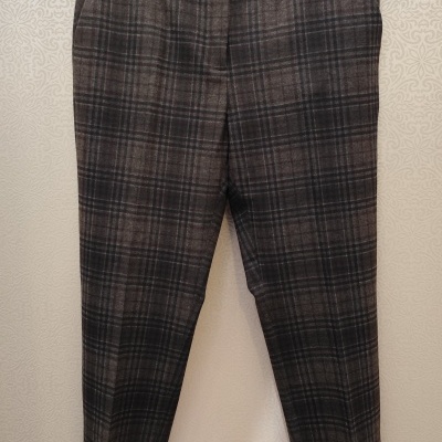 Calças sociais de xadrez castanho escuro e preto penduradas num cabide