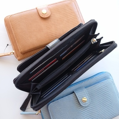 Três carteiras texturizadas em bege, preto e azul claro, uma aberta mostrando compartimentos internos.