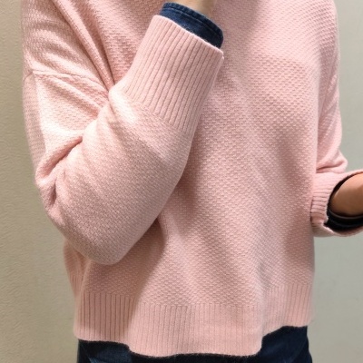 Pulôver de malha rosa com gola alta usado sobre camisa azul escura