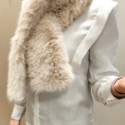 Pessoa com blusa branca e cachecol felpudo bege claro