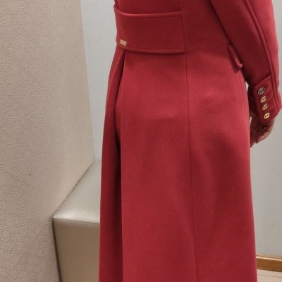Casaco vermelho comprido com cinto e botões dourados, visto de lado