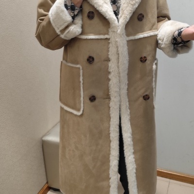 Casaco comprido bege com pelo branco e botões castanhos em fundo interior neutro.