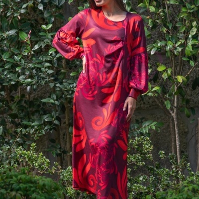 Vestido longo vermelho com padrão, mangas bufantes, botas e fundo de plantas