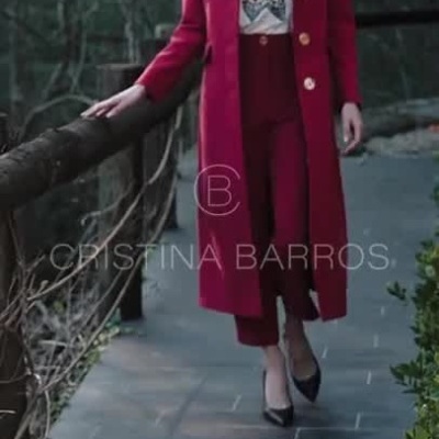 Modelo com casaco vermelho, calças e t-shirt branca com fundo de vegetação