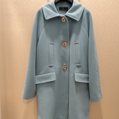 Casaco azul claro com botões castanhos pendurado num cabide preto com a marca CRISTINA BARROS