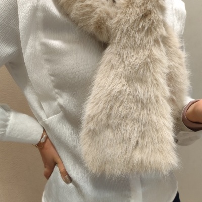 Cachecol de pelo sintético bege claro sobre camisa branca texturizada e calças escuras