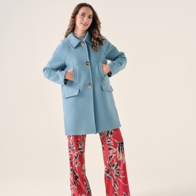 Mulher com casaco azul claro e calças vermelhas com padrão floral