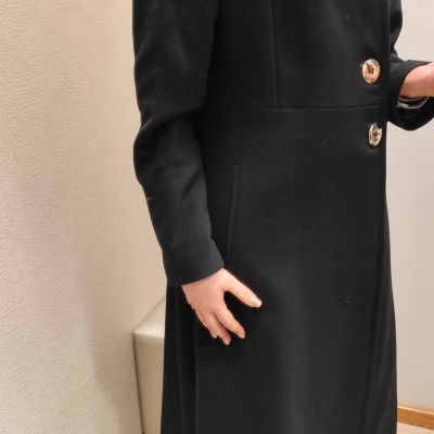 Casaco longo preto com três botões grandes e gola alta.