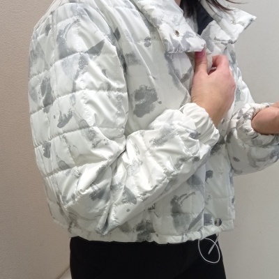 Casaco acolchoado branco com padrão cinza e botões de pressão