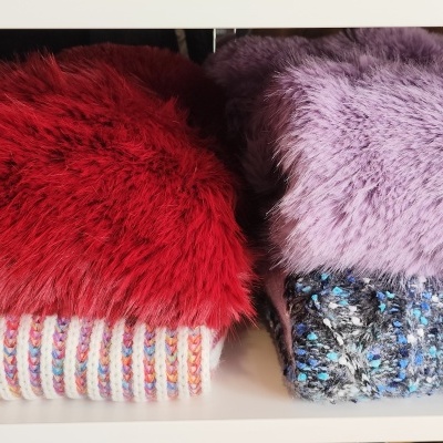 Duas mantas felpudas vermelha e lilás em pilhas sobre prateleira branca