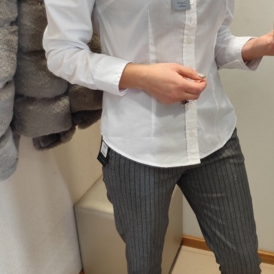 Camisa branca de algodão com colarinho e botões combinada com calças cinzentas às riscas e sapatos pretos