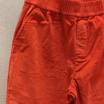 Calças veludo cotelê laranja com cintura elástica penduradas em cabide preto