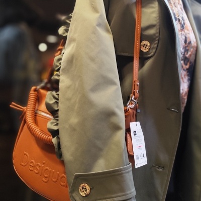 Gabardina verde e mala castanha com o texto Desigual num manequim