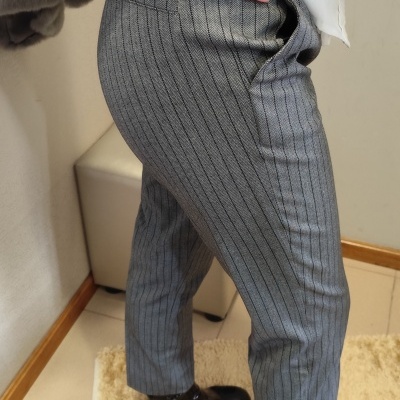 Calças cinzentas de riscas verticais com botas pretas e camisa branca