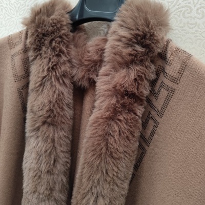 Casaco castanho com gola de pelo castanho claro num cabide preto