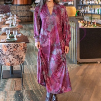 Mulher usando vestido comprido roxo com padrão abstrato e botas castanhas em restaurante