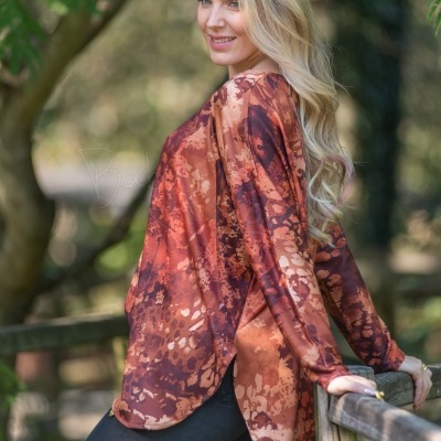 Mulher com túnica castanha de padrão abstrato em ambiente exterior de natureza