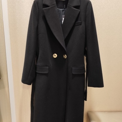 Casaco preto comprido com botões dourados na cabideira da loja