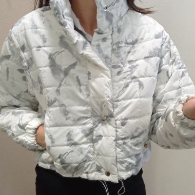 Casaco acolchoado branco com padrão cinzento abstrato e fecho com botões de pressão