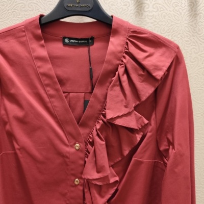 Blusa rosa com botões dourados e folhos, pendurada num cabide preto CRISTINA BARROS