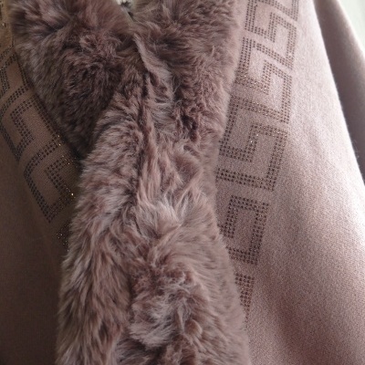 Cachecol de pelo castanho enrolado no pescoço de manequim com camisola rosa com padrão geométrico e botão