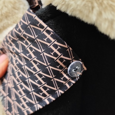 Casaco preto com gola de pelo bege e aba estampada com letras FAV e botão transparente