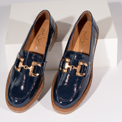 Mocassins azul escuro brilhantes com fivela dourada e sola castanha clara.