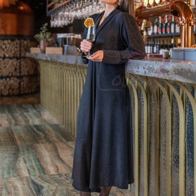 Mulher com vestido preto longo e sapatos de salto num bar moderno