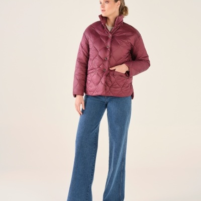 Mulher vestindo casaco acolchoado vinho com calças de ganga azuis