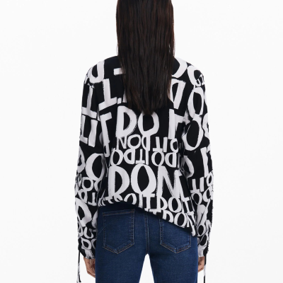 Camisola preta com estampado branco de letras, vista de costas, com jeans azul.