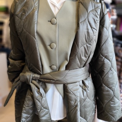 Casaco acolchoado verde-oliva com cinto e colete verde claro com camisa branca em manequim