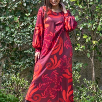 Vestido comprido vermelho com padrão floral laranja usado por mulher em jardim